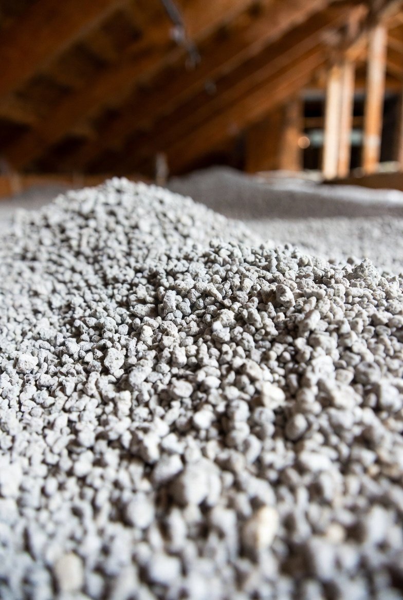 : Close-up of vermiculite attic insulation showing loose-fill pebble-like granules